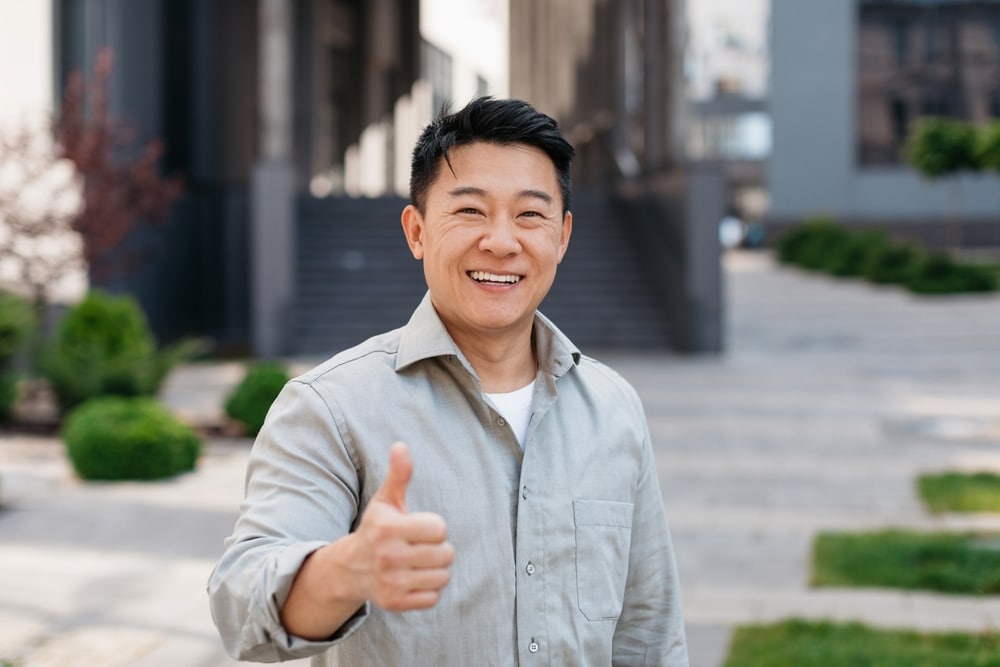 A happy man gives a thumbs-up for his new Immediate Dentures at All Valley Dental