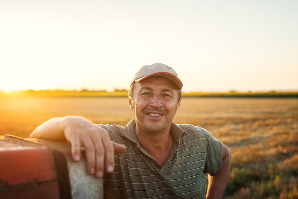 A happy farmer smiling in his field after getting Implant-Supported Bridges at All Valley Dental