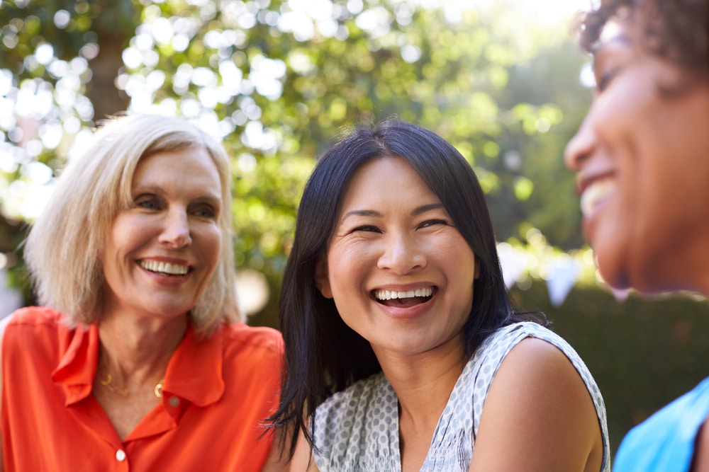 Friends laugh together, sharing confident smiles thanks to Restorative Dentistry at All Valley Dental